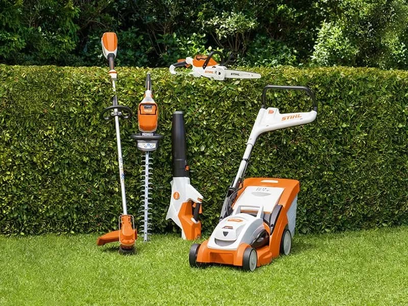 Assortment of STIHL outdSTIHL outdoor power equipment on display at Weiders Hardwareoor power equipment, including a mower, trimmer, hedge trimmer, chainsaw, and blower, displayed on a lawn.